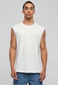 T-shirt blanche sans manches à coupe décontractée, en coton doux. Présente un col rond et un minimalisme dans les détails de couture.