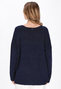 Navy Oversized-Pullover mit strukturiertem Finish, weitem Ausschnitt, gerippten Bündchen und Saum. Die Rückansicht zeigt ein Etikett am Kragen.