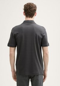 Ciemnoszary polo z subtelnym paskowanym wzorem, krótkimi rękawami i klasycznym kołnierzykiem; wykonany z gładkiego, lekkiego materiału.