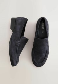 Mocassini in suede blu scuro con punta rotonda e dettagli cuciti, dotati di un tacco basso a blocco e suola esterna in gomma nera liscia.