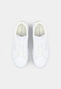 Baskets basses blanches en cuir lisse, dotées d'un bout arrondi, de lacets plats et d'un logo sur le côté. Design minimaliste sans motifs.