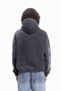 Mikina s kapucí v tmavě šedé barvě, s texturovanou látkou, volným střihem a grafickými detaily na rukávech. Nosit s světle modrými džíny.