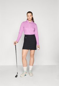 Golf uniforma, kurioje yra šviesiai violetinė ilgarankovė polo marškiniai su užtrauktuku, derinama su juoda mini sijonu. Pilkos golfo bateliai su mėlynomis detalėmis.