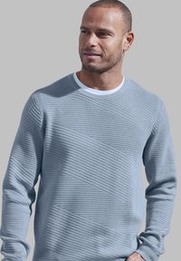 Hellblauer Pullover mit einem strukturierten diagonalen Muster, Rundhalsausschnitt und gerippten Bündchen. Hergestellt aus einem weichen Strickmaterial.