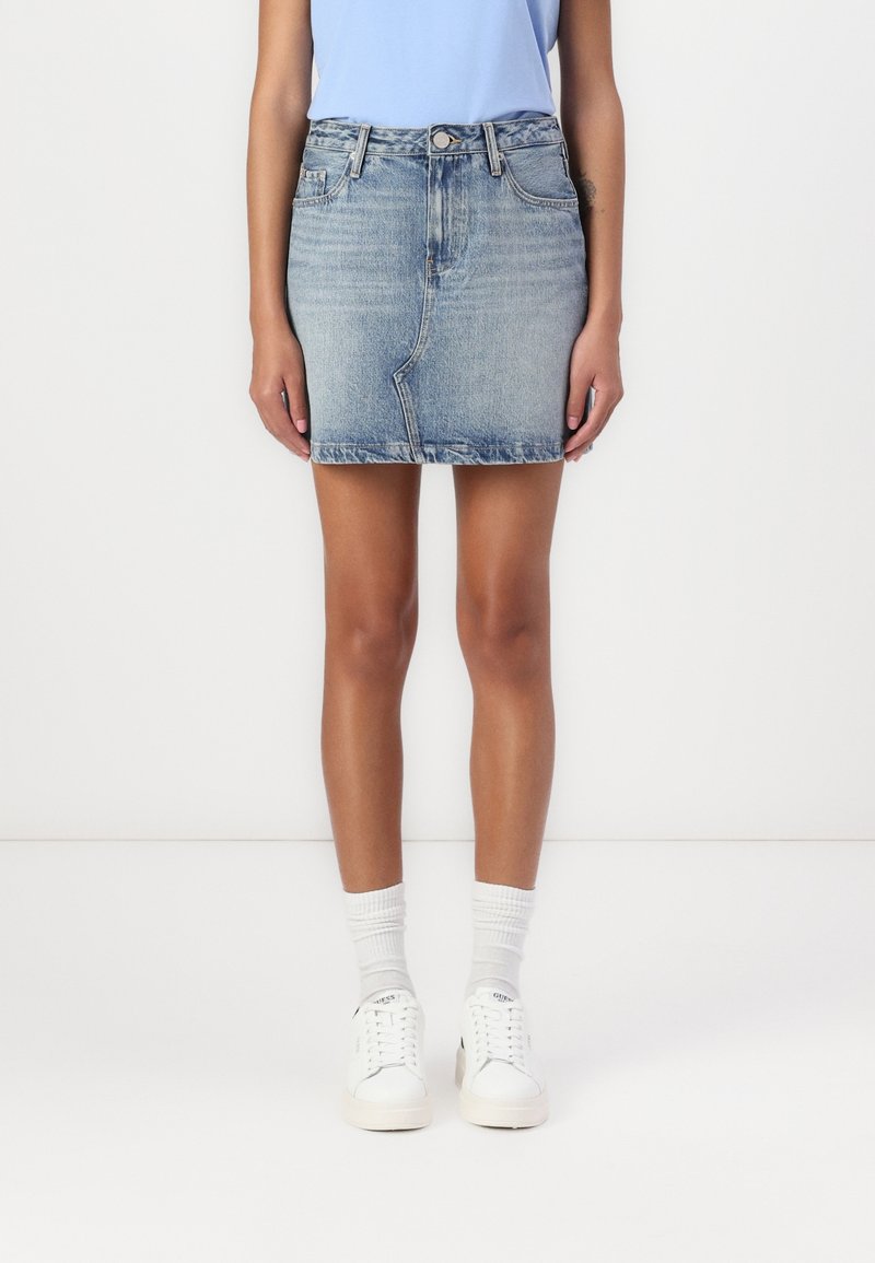Light blue denim skirt with a fitted design, frayed hem, and classic five-pocket styling, paired with white sneakers and socks.