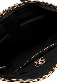 Schwarzes Innenfutter einer Tasche mit tierischem Druck. Merkmale sind eine Reißverschlusstasche und eine strukturierte Oberfläche. Das Design ist geräumig und funktional.