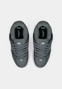 Grijze sportieve schoenen van glad leer met witte zolen, voorzien van geperforeerde accenten en een gevoerde binnenkant. De veters zijn gelijkmatig gestrikt.