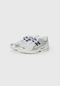 Silver and white athletic shoes with mesh upper, navy accents, textured sole, and lace-up front. Notable logo on the side.