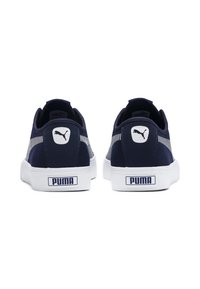 Marineblå mockaskor med vita gummisålar, med en Puma-logotyp på baksidan och randig detalj på sidorna.