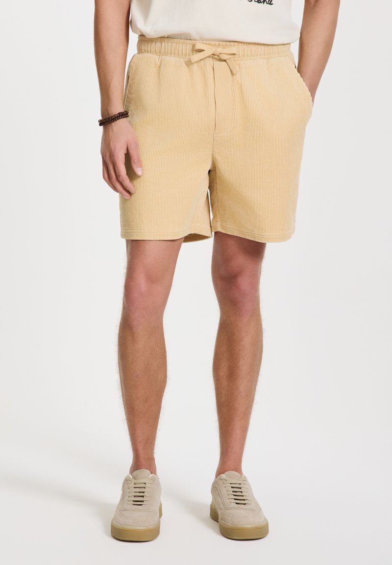 Beige puuvillainen corduroy-shortsit, joissa on joustava vyötärö ja naru, sivutaskut ja suora leikkaus.