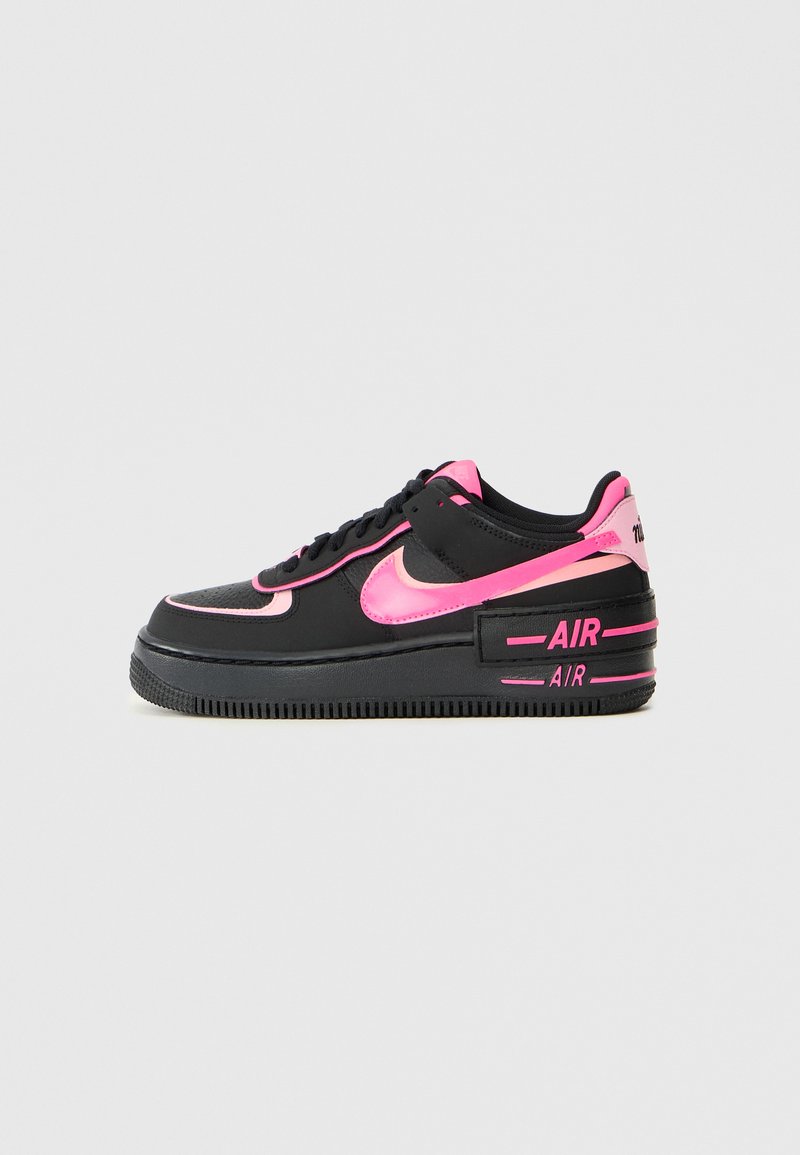 Čierne tenisky Nike Air Force 1 majú lesklý ružový Swoosh, obrubu a akcenty, s textúrovaným zvrškom a gumovou podrážkou.