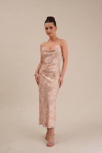 Vestido de cetim com padrão floral, na cor rosa claro, com alças finas, silhueta ajustada e comprimento até meio da panturrilha, combinado com sapatos de salto com tiras.