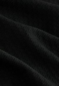 Črno teksturirano blago z drobnimi, subtilnimi vzorci. Material se zdi mehak in rahlo raztegljiv, s prikazovanjem različnih odtenkov črne barve.