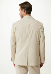 Beige linne kavaj med en enda ventil bak, med en notchad krage och två knappar vid ärmarna, slät textur.