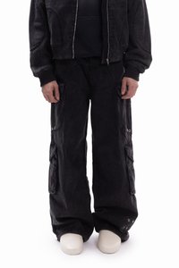 Črni denim jakna s skrajšanim dizajnom, kombinirana z ohlapnimi cargo hlačami z velikimi žepi in kovinskimi okraski.