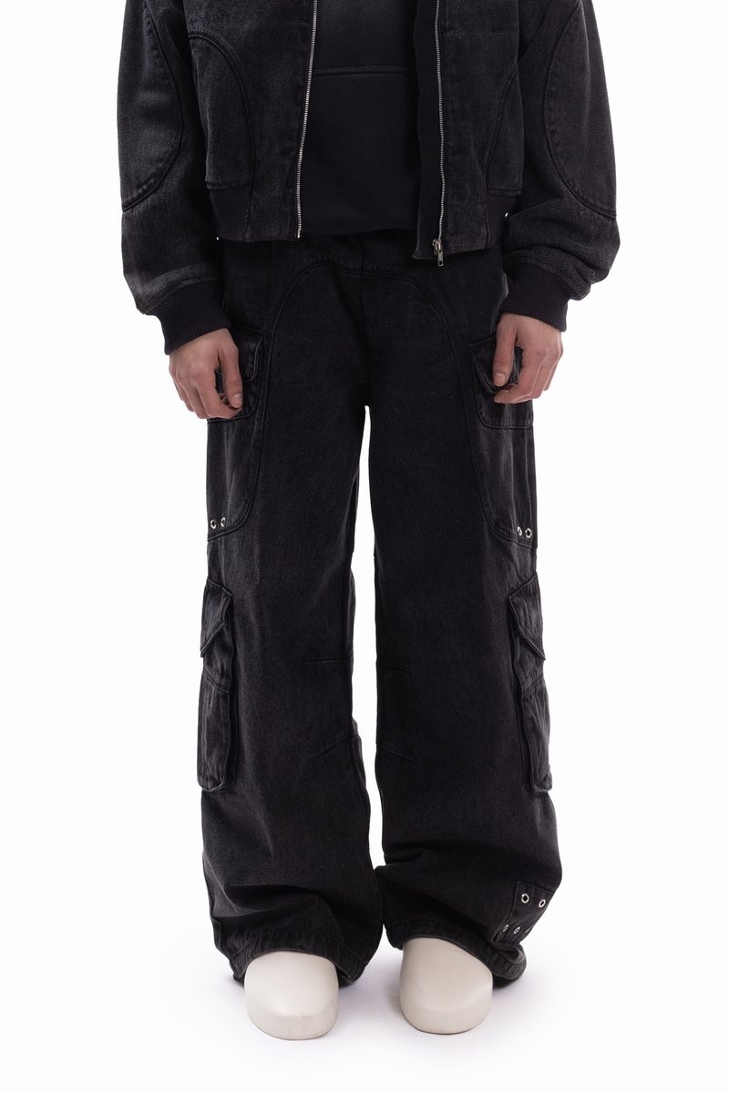 Črni denim jakna s skrajšanim dizajnom, kombinirana z ohlapnimi cargo hlačami z velikimi žepi in kovinskimi okraski.