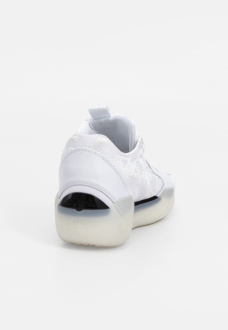 Zapatilla blanca con un upper texturizado, talón de cuero suave, suela translúcida y una pequeña tira en la parte trasera para facilitar el uso.
