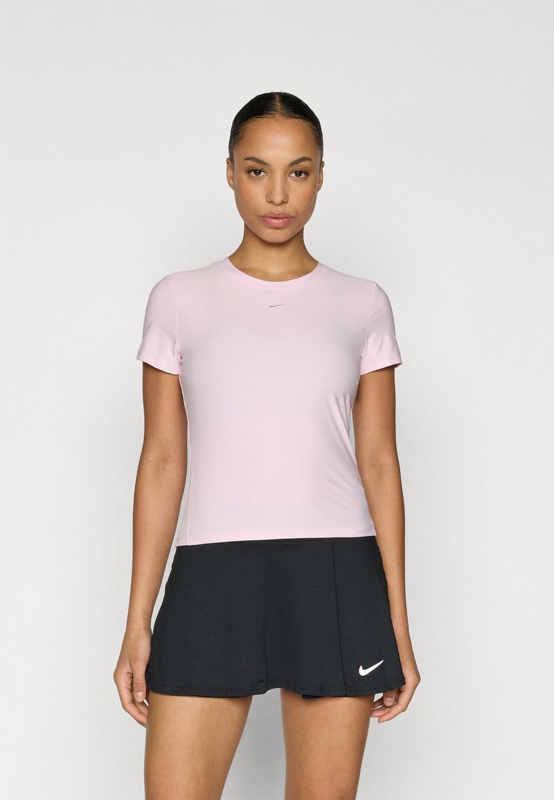 Top sportivo rosa manica corta con scollo rotondo e logo Nike. Abbinato a una gonna da tennis nera svasata con dettaglio logo bianco.