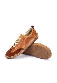 Zapatos de cuero marrón con acentos de ante, presentando un diseño de cordones, punta redondeada y bordes cosidos en contraste. Suela de goma texturizada.
