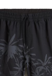 Bañador negro con un estampado oscuro de hojas de palmera. Cuenta con una cinturilla elástica, un cordón ajustable y una textura suave.