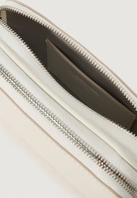 Lommebog med lynlås i en creme og beige farveskala, struktureret stof og glat læderindvendig med flere kreditkortlommer.