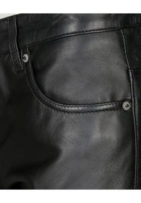 Zwarte leren broek met een gladde textuur, zichtbare stiksels en een voorzak met een metalen knoopdetail.