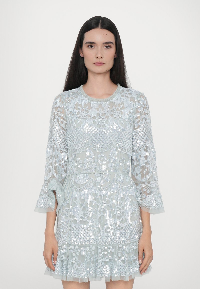 Abito azzurro chiaro con sovrapposizione di pizzo trasparente, progettato in modo intricato con paillettes, maniche a campana e vita cinte. Presenta un orlo a strati con volant.