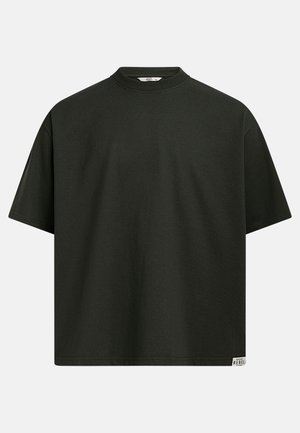 Σκούρο πράσινο φαρδύ κοντομάνικο μπλουζάκι με στρογγυλή λαιμόκοψη και μια μικρή ορθογώνια ετικέτα με το λογότυπο «Rebel» στο κάτω μέρος της ραφής, σε λευκό φόντο.