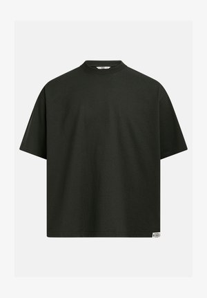 T-shirt oversize a maniche corte di colore verde scuro con scollatura tonda e una piccola targhetta rettangolare con il logo "Rebel" sull'orlo inferiore, su sfondo bianco.