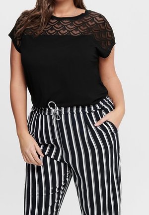 Zwarte top met doorschijnend, patroonrijke schouderdetail, gecombineerd met zwart-wit gestreepte, wijde broekspijpen met een elastische tailleband en zakken.