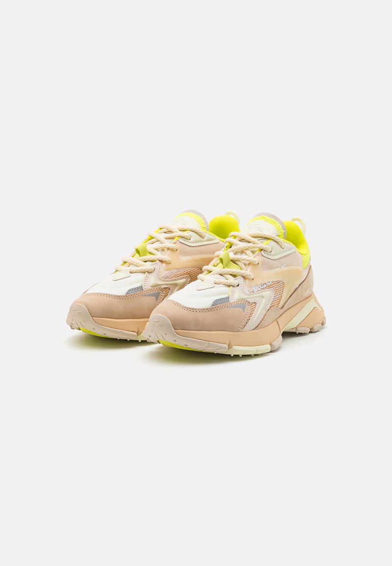 Sneakers z kremową i beżową cholewką, żółtymi akcentami, teksturowaną siateczką, wyściełanym językiem i grubą gumową podeszwą. Sznurówki w dopasowanym odcieniu.