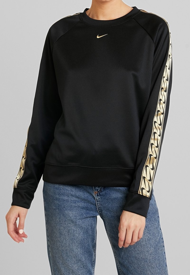 Czarna bluza Nike o gładkiej fakturze, z akcentami w postaci złotych wzorów łańcuchów na rękawach oraz małym logo na piersi.