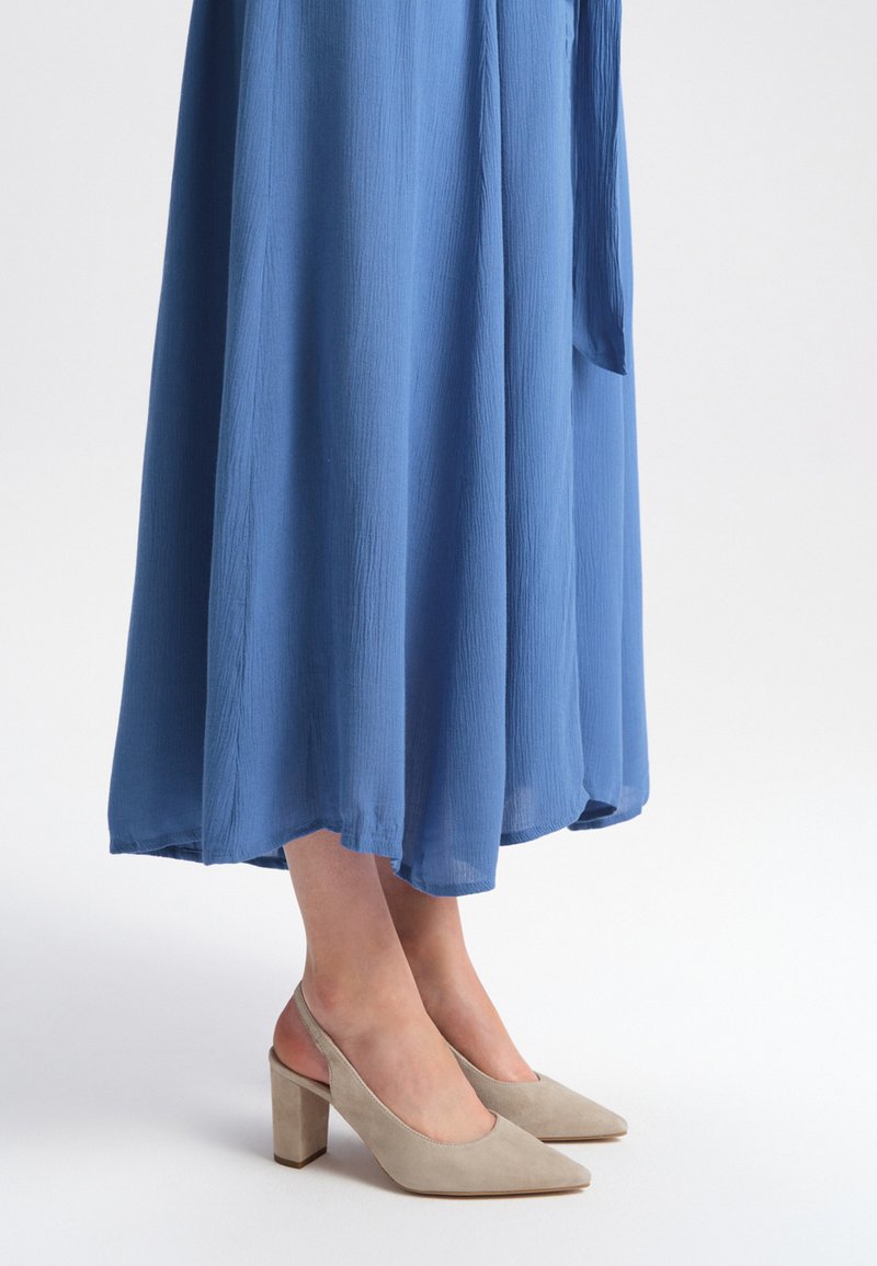 Blue, flowing maxi dress with a textured fabric, paired with beige suede slingback heels featuring a chunky heel and pointed toe.