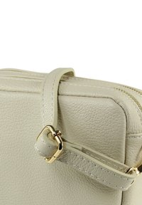 Hellgraue Lederhandtasche mit strukturierter Oberfläche, ausgestattet mit einem abnehmbaren Riemen und goldfarbenen Beschlägen. Reißverschluss entlang der oberen Kante.