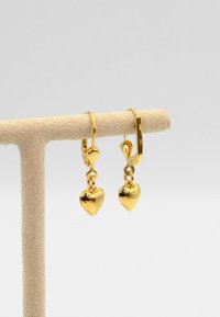 Goldene, herzförmige Tropfohrringe mit polierter Oberfläche und hängendem Design. Sie verfügen über einen Klappverschluss und eine glatte, glänzende Oberfläche.