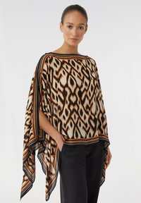 Lekki, wzorzysty poncho w kolorach kremowym, czarnym i pomarańczowym z geometrycznym wzorem. Posiada szerokie rękawy oraz kontrastowy dół.