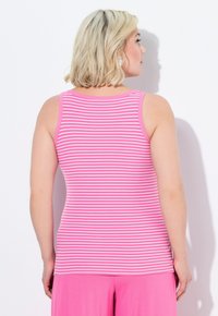 Top con righe rosa, realizzato in tessuto a coste, con scollatura a barca e spalline larghe. Indossato con un pantalone rosa, esposto su uno sfondo bianco.