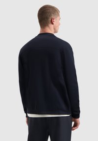 Marineblauwe pullover met een gestructureerde breiwerk, ronde halslijn en geribde manchetten, met een gladde, strakke afwerking en een minimalistisch ontwerp.