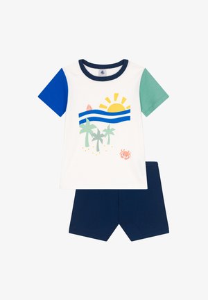 Weißes Baumwoll-T-Shirt mit kurzen Ärmeln und blauen sowie grünen Ärmeln, verziert mit Grafiken von Sonne, Wellen, Palmen und einem Krebs. Kombiniert mit navyblauen Shorts.