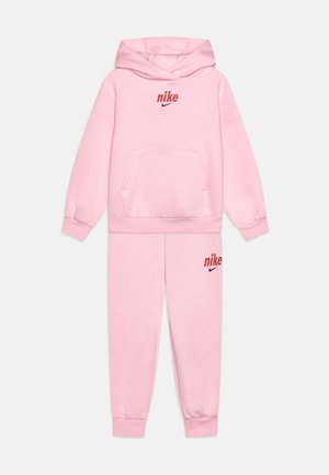 Ensemble de sweat à capuche et de survêtement Nike rose, featuring une poche kangourou, des poignets côtelés, et des accents de logo rouge sur le haut et le bas.