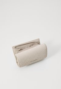 Calvin Klein šviesiai ruda piniginė, pagaminta iš tekstūruotos medžiagos, su užtrauktuku uždarymu ir iškilniu logotipu priekyje. Kompaktiška ir stačiakampio formos.