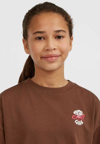 Brun bomull T-shirt med rund krage, avslappnad passform och färggrafisk brodyr av "Chill Wave" på vänstra bröstområdet.
