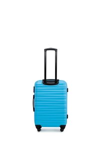 Valise rigide de couleur bleu vif, avec des rainures verticales, une poignée noire rétractable et quatre roues noires pour la mobilité.