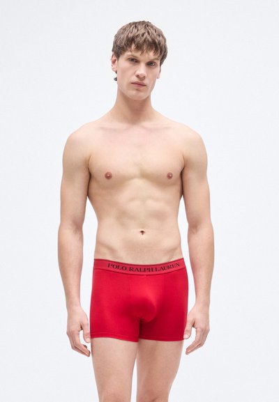 Boxer rossi realizzati in tessuto elasticizzato, con una cintura nera con logo e una vestibilità aderente, progettati per comfort e supporto.