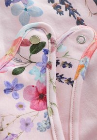 Blumenmusterstoff in Pink mit blauen und lila Blumen, metallischer Druckknopfverschluss und kontrastierende Naht entlang der Kanten.