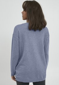 Maglione blu a maglia con maniche lunghe, vestibilità rilassata, scollatura tonda e orlo a coste. Texture morbida e delicato motivo melangiato.
