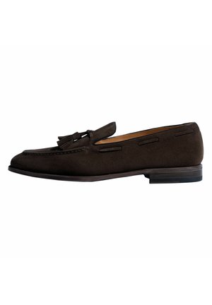 Mocasines de ante marrón con detalle de borlas, punta redonda, forro de cuero y tacón apilado. Presenta costuras tono sobre tono y cortes laterales.