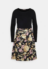 Robe noire à manches longues avec un col rond et une jupe à motif floral dans des tons de rose pastel, jaune et vert sur un fond noir.