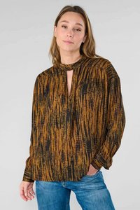 Bruine en zwarte geblokte blouse met een iets open hals, lange mouwen en een relaxte pasvorm. De stof lijkt zacht en gestructureerd te zijn.