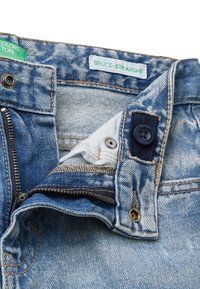 Jeans in denim blu con taglio dritto, dotati di zip sul davanti, chiusura a bottone e una patch con il testo "BRUCE-STRAIGHT". Dettagli con effetto usurato.